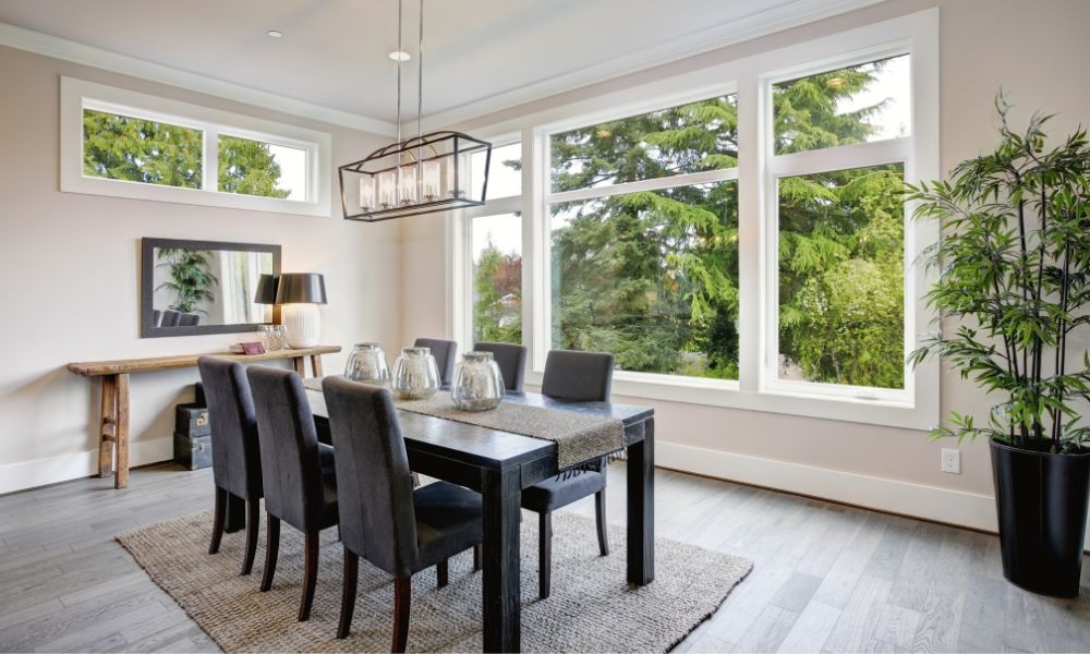A dining room with a black dining room table next to a large window.
