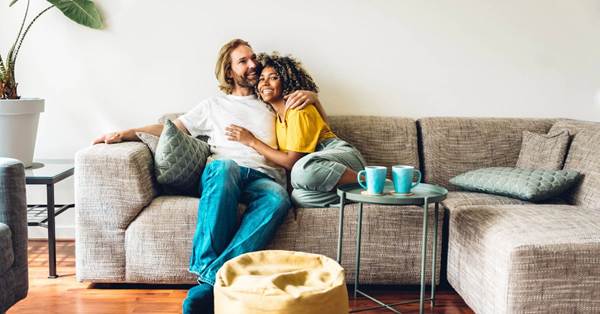 A couple holding and sitting on a couch